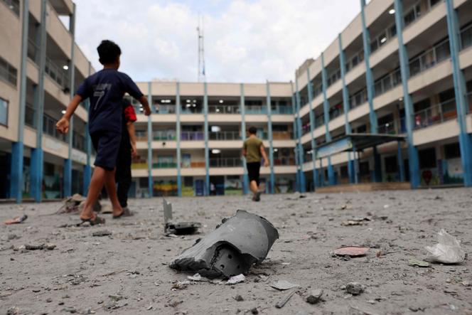 Palestinian children walk past debris in the courtyard of a school run by the United Nations Relief and Works Agency for Palestine refugees (UNRWA) following Israeli airstrikes targeting Gaza City on October 9, 2023. 
