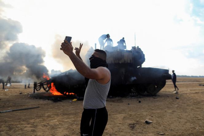 A man takes a photo in front of a destroyed Israeli tank near the border with the Gaza Strip on October 7.