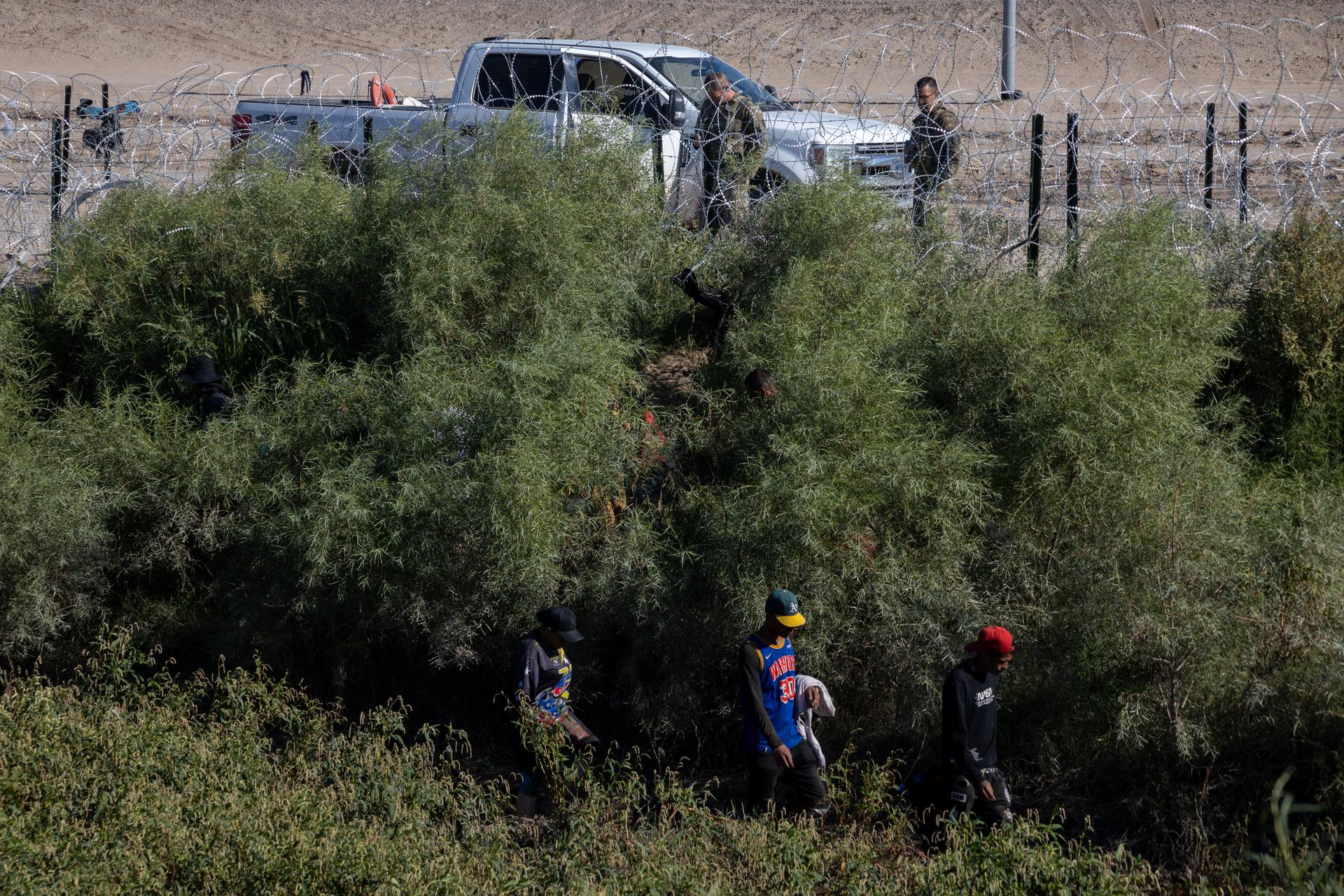 A group of migrants walk along the Rio Grande, looking for a way to enter the United States under the barbed wire installed by the Texas National Guard to prevent irregular crossings. Ciudad Juarez (Mexico), October 4, 2023.