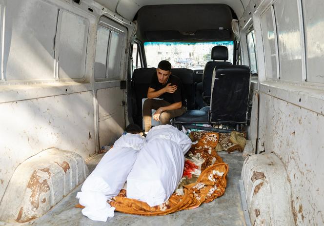 A Palestinian stands beside the bodies of his loved ones in Gaza on October 11, 2023.