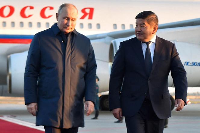 Russia's President Vladimir Putin walks with Chairman of the Cabinet of Ministers of Kyrgyzstan Akylbek Zhaparov (R) upon his arrival at the Manas International Airport in Bishkek, October 12, 2023.