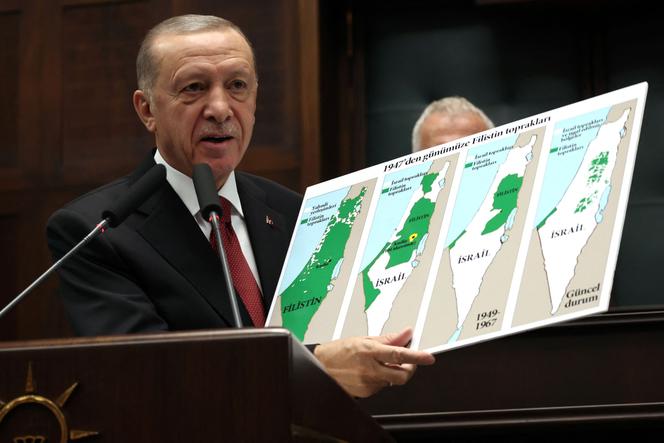 Turkish President Recep Tayyip Erdogan holds a placard showing the evolution of the lands of Israel and Palestine, at the Turkish Grand National Assembly, Ankara, October 11, 2023.