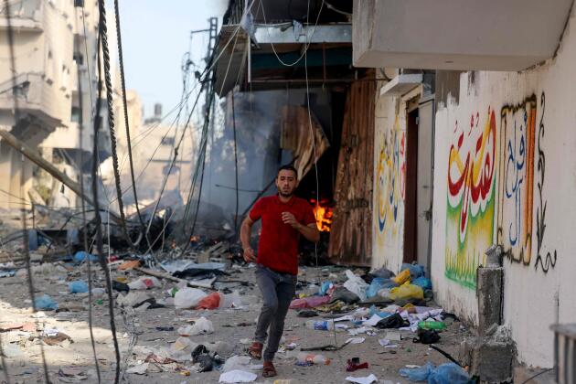 Un palestino corre entre los escombros de un edificio alcanzado por un ataque aéreo israelí, Gaza, 13 de octubre de 2023. 