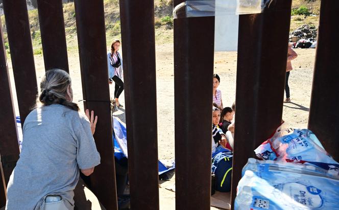 Migrants at the US-Mexico border wall on October 10, 2023 in San Diego, California.