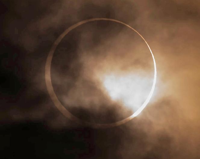 The annular solar eclipse appears from behind clouds above Skinner Butte in Eugene, Oregon, on October 14, 2023.