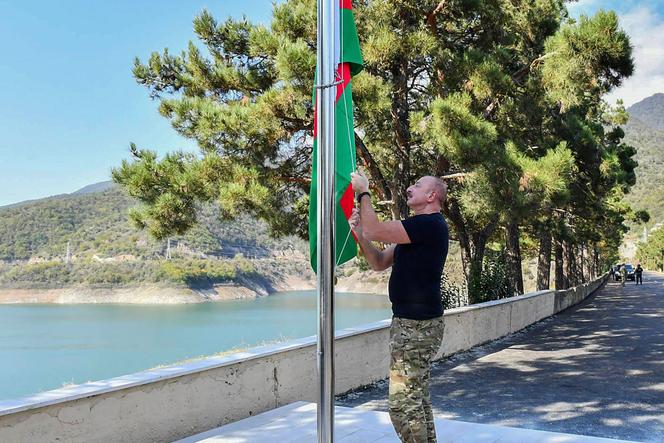 This photograph taken and released by Azerbaijani Presidential Press Office on October 15, 2023, shows Azerbaijan's President Ilham Aliyev rising a national flag of Azerbaijan on a bank of the Sarsang reservoir in Nagorno-Karabakh region.