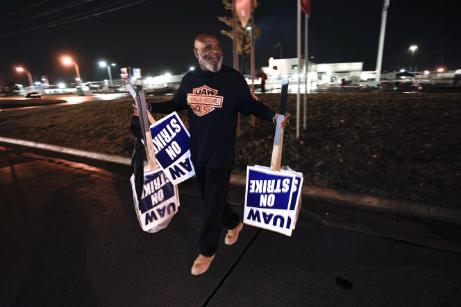 A United Auto Workers union worker removes signs calling for a strike from the Ford embly plant in Wayne, Michigan, October 25, 2023.