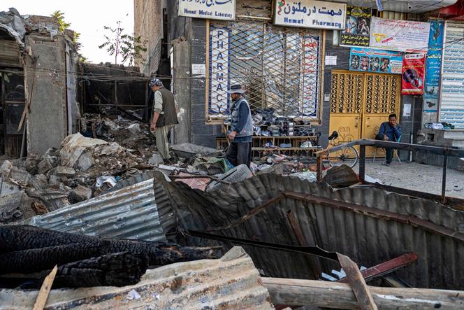 Afghan shoe sellers (C) work outside their charred shop, a day after an explosion took place in their above floor at the Mellat boxing club in the Dasht-e-Barchi neighborhood of Kabul on October 27, 2023.