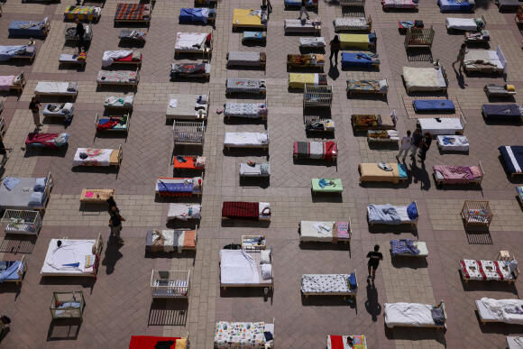 Des personnes regardent des matelas et des lits faisant partie de l’installation « Empty Beds » initiée par les survivants du kibboutz Nir Oz et les familles des otages détenus à Gaza, sur une place publique à Jérusalem, le 30 octobre 2023.