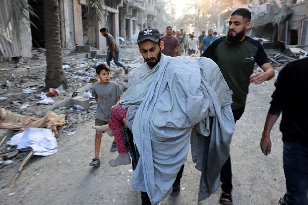 A man carries the body of a young girl pulled from a collapsed building after an Israeli bombardment in the Nuseirat refugee camp in the central Gaza Strip, October 30, 2023.