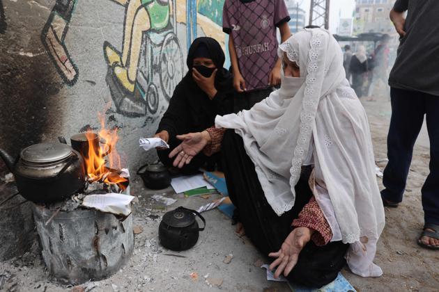 Women burn paper to heat water for tea in Rafah, southern Gaza Strip, October 28, 2023.