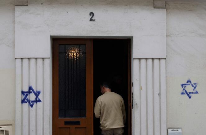 A man enters a building tagged with blue Stars of David, in the 14th arrondissement of Paris, on October 31, 2023.