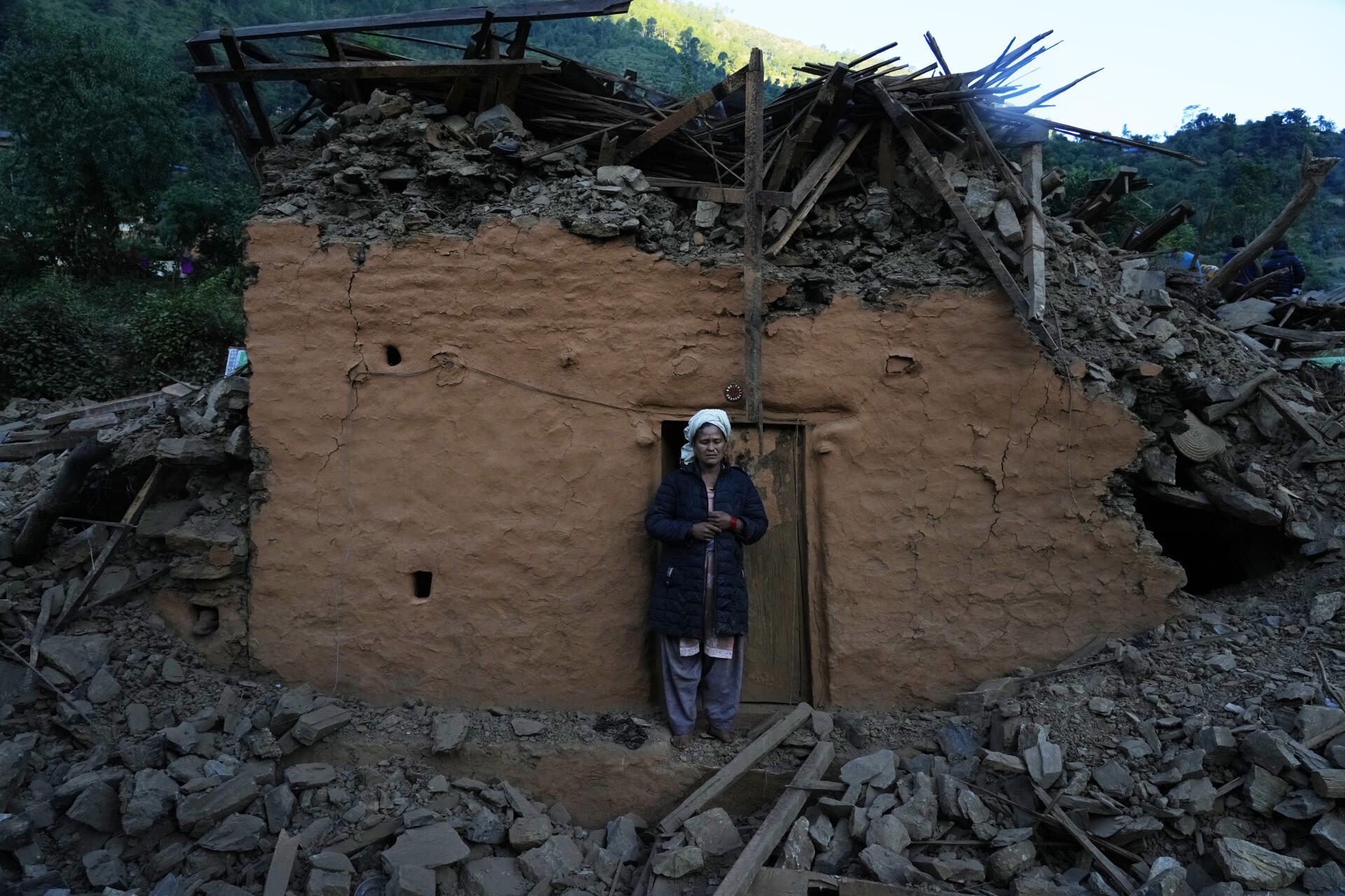 Une femme devant une maison endommagée par le tremblement de terre dans le district de Jajarkot, dans le nord-ouest du Népal, dimanche 5 novembre 2023.