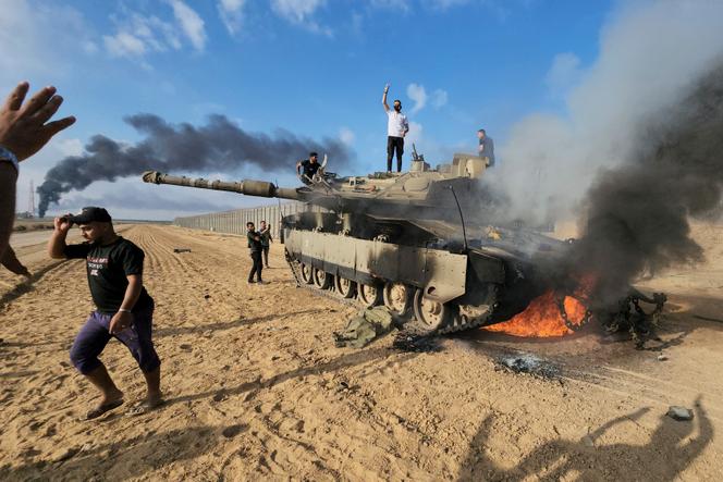 Según Honest Reporting, la cobertura de los primeros enfrentamientos por parte de fotoperiodistas palestinos de AP y Reuters sería sospechosa, como esta fotografía de un tanque destruido cerca de la frontera.  Hassan Eslaiah, su autor, fotografiado en el pasado con un líder de Hamás, niega haber tenido conocimiento del ataque.