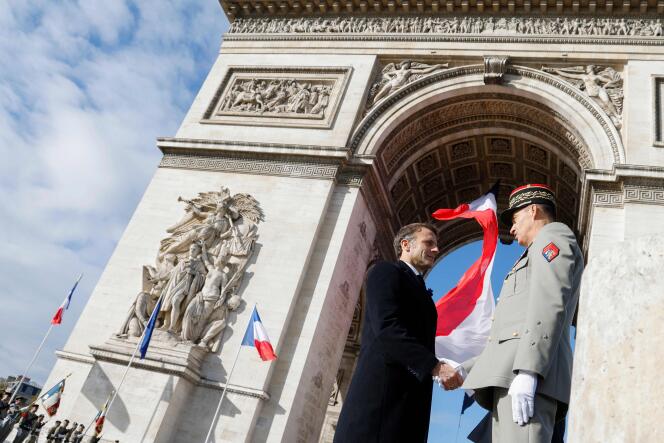 Le président Emmanuel Macron a servi la main du gouverneur militaire de Paris, Christophe Abad, après le ravivage de la flamme du Soldat inconnu, samedi 11 novembre.