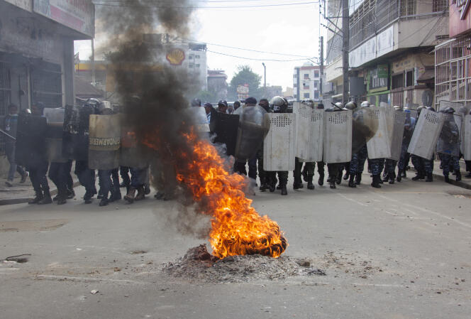 Agentes de policía se reunieron frente a neumáticos en llamas, durante las manifestaciones contra la celebración de las elecciones presidenciales malgaches, el 11 de noviembre de 2023, en Antananarivo.