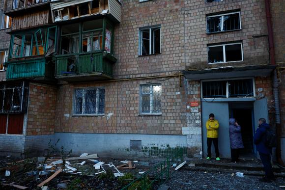 Des habitants se tiennent à côté de leur immeuble endommagé par des frappes de drones russes, dans le cadre de l’attaque de la Russie contre l’Ukraine, à Kiev, en Ukraine, le 25 novembre 2023.