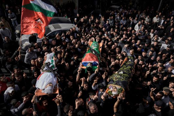 Des personnes en deuil portent les corps d’Asaad Al-Dam, à droite, Mahmoud Abou Al-Hayja, au centre, et Ammar Abou Al-Wafa, drapés dans les drapeaux du groupe militant du Jihad islamique palestinien et du Hamas, lors de leurs funérailles dans le campy  de réfugiés de Jénine, en Cisjordanie, le dimanche 26 novembre 2023.