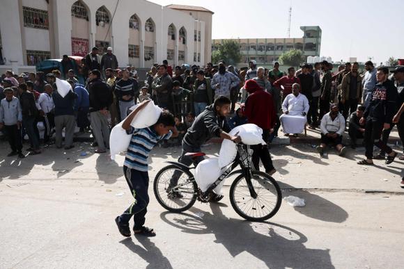 Un enfant et un jeune homme transportent des sacs d’aide humanitaire, à Rafah, dans le sud de la bande de Gaza, le 26 novembre 2023.