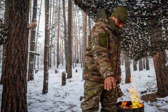Un soldat de la 2e légion internationale des forces armées ukrainiennes se réchauffe les mains à l’aide d’un brûleur artisanal, près d’une ligne de front, dans un lieu non divulgué de la région de Donetsk, en Ukraine, le 23 novembre 2023.