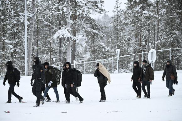 Des gardes-frontières finlandais escortent des migrants à leur arrivée au poste-frontière Raja-Jooseppi vers la Russie à Inari, dans le nord de la Finlande, le 25 novembre 2023.