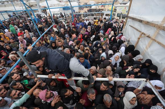 Des Palestiniens se rassemblent en attendant de recevoir des sacs de farine distribués par l’Office de secours et de travaux des Nations unies determination    les réfugiés de Palestine dans le Proche-Orient (UNRWA) pendant la trêve temporaire entre le Hamas et Israël, à Khan Younès, dans le sud de la bande de Gaza, le 27 novembre 2023.