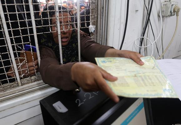 Une femme palestinienne présente sa carte de rationnement determination    recevoir des sacs de farine distribués par l’UNRWA, pendant la trêve, à Khan Younès, dans le sud de la bande de Gaza, le 27 novembre 2023.