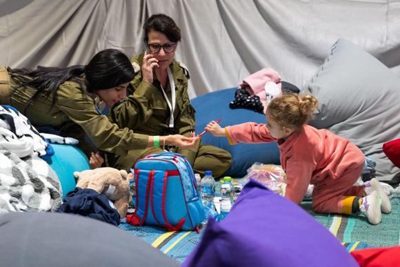 Sur cette photograph  publiée par le bureau de presse du gouvernement israélien, des soldats jouent avec Yahel Neri, la fille de l’ancien otage Adi Shoham, qui a la treble  nationalité israélienne et allemande, après que la mère et la fille ont été libérées, le 26 novembre 2023.