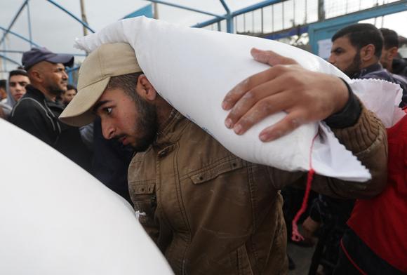 Un Palestinien porte un sac de farine distribué par l’UNRWA, à Khan Younès, dans le sud de la bande de Gaza, le 27 novembre 2023.