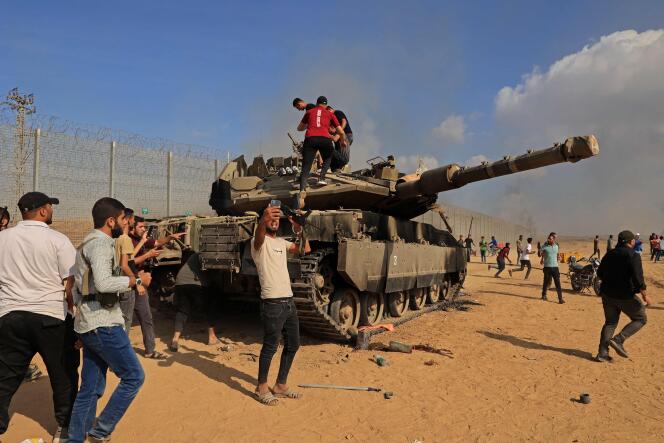 Palestinians take control of an Israeli Merkava battle tank after crossing the border into Israel from Khan Yunis, in the southern Gaza Strip, on October 7, 2023.