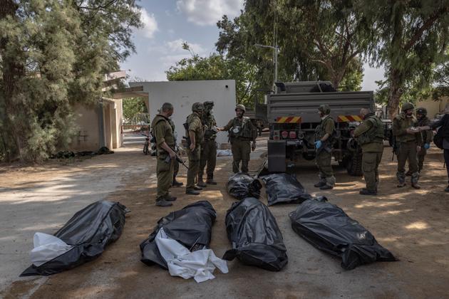 Israeli soldiers recover the bodies of victims abandoned in the village of Kfar Aza, near the border with Gaza, on October 10, 2023.