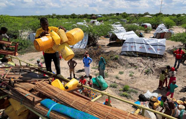 Families displaced by floods unload their belongings from a truck to set up camp after heavy rains in Garsen, Kenya, November 23, 2023.