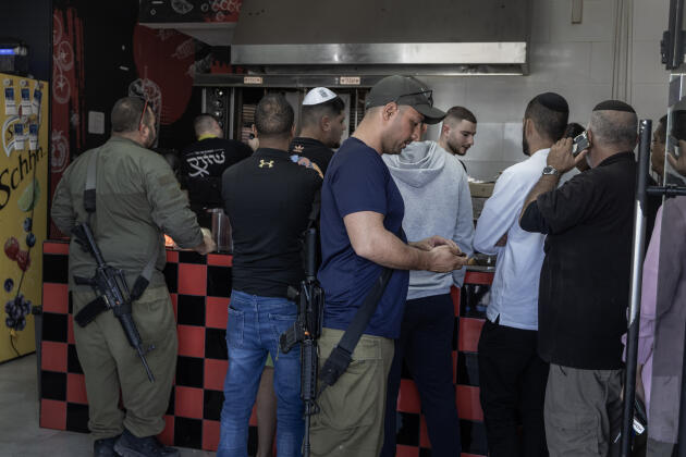 Israeli soldiers buy a sandwich in one of the few shops to reopen in Sderot, December 3, 2023.