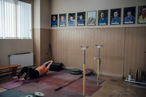 Une membre de l’équipe nationale d’haltérophilie à l’entraînement. Au mur, les portraits des athlètes stars de la discipline. A Kiev, le 5 décembre 2023.