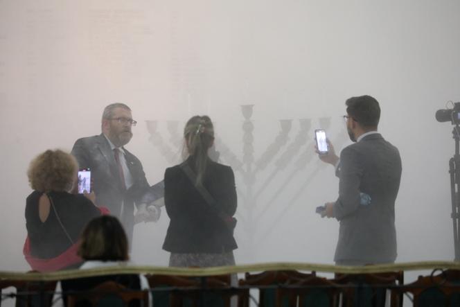 Polski skrajnie prawicowy poseł Krzegorz Brown gaśnie pożar gaśnicą przed siedmioramienną świecą na środku parlamentu we wtorek, 12 grudnia 2023 r.
