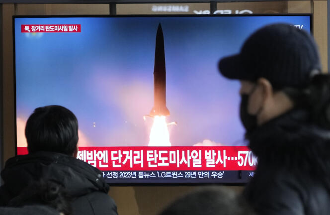Des passants regardent un programme d’informations sud-coréen diffusant une image du lancement d’un missile nord-coréen, sur un écran à la gare de Séoul, le 18 décembre 2023.