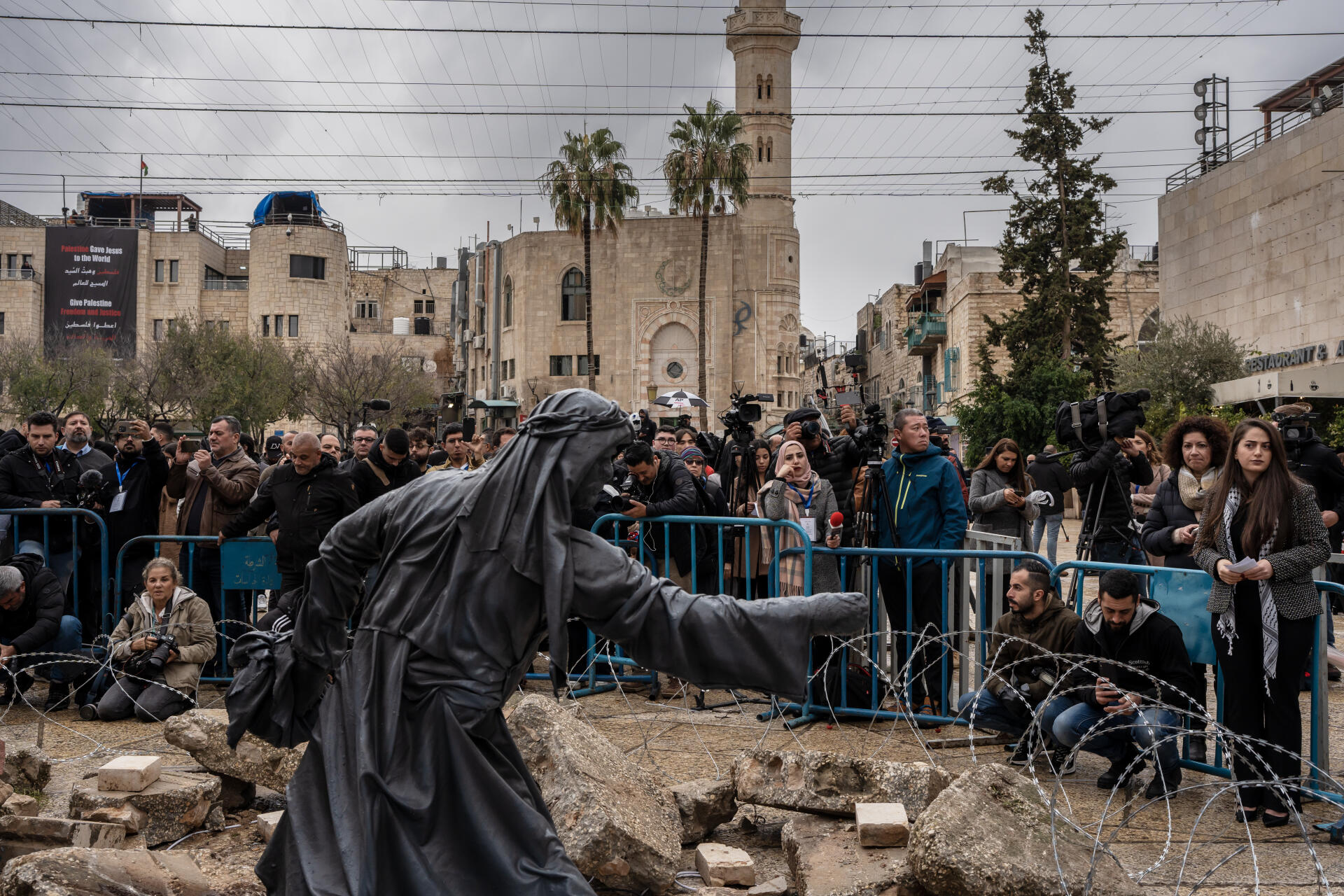 Periodistas frente a “Natividad bajo los escombros”, una obra de Tariq Salsa que reemplaza el belén este año para recordar el horror actual en Gaza, en Belén, Cisjordania, el 24 de diciembre de 2023. 