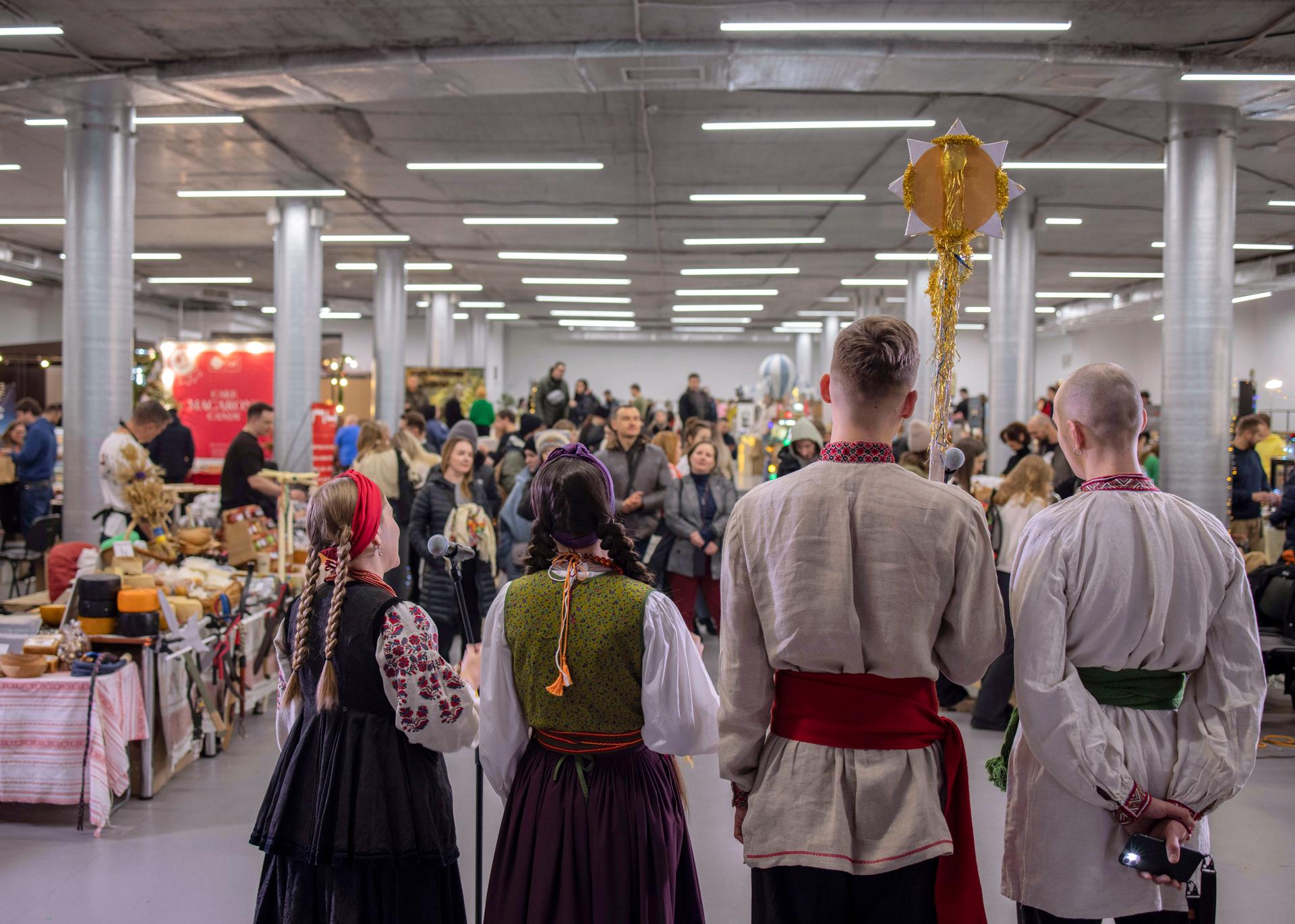 A group of young Ukrainians sing carols at a Christmas fair in downtown Kyiv on December 24, 2023.