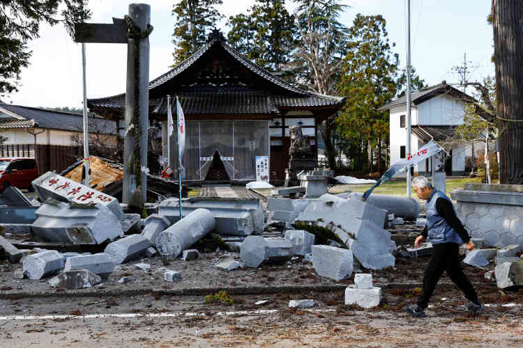 Un uomo cammina vicino a un santuario danneggiato a Ojima, prefettura di Ishikawa, Giappone, 2 gennaio 2024.