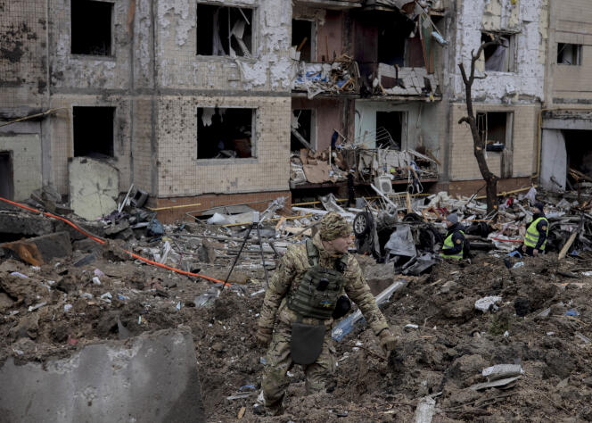 Ukraiński żołnierz w pobliżu apartamentowca po rosyjskim nalocie, w Kijowie, 2 stycznia 2024 r.