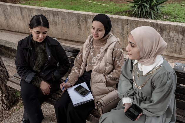 Architecture students Rand, Rana and Nebal listen to their online course in the gardens of Birzeit University on December 21, 2023