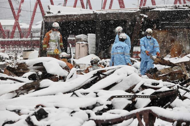 Los bomberos buscan personas desaparecidas en las ruinas carbonizadas del mercado de Wajima mientras la nieve cubre parte de la zona del desastre, el 8 de enero de 2024, una semana después del terremoto.
