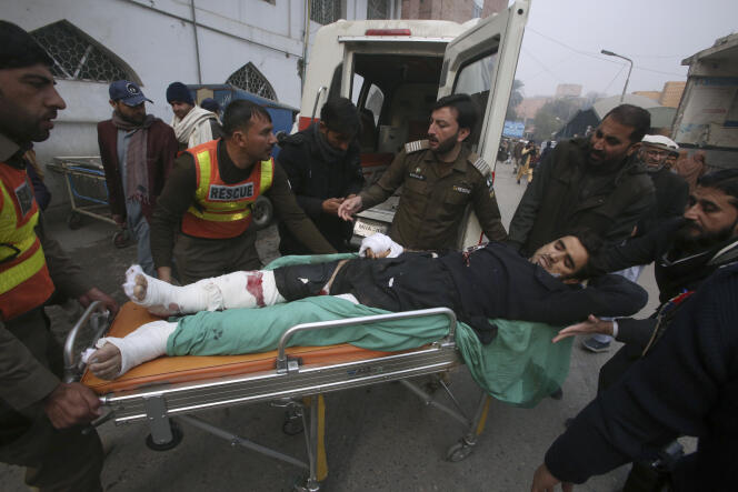 Rescue workers and volunteers carry an injured police officer, the victim of a bomb attack, upon arrival at a hospital in Peshawar, Pakistan, Monday, Jan. 8, 2024.