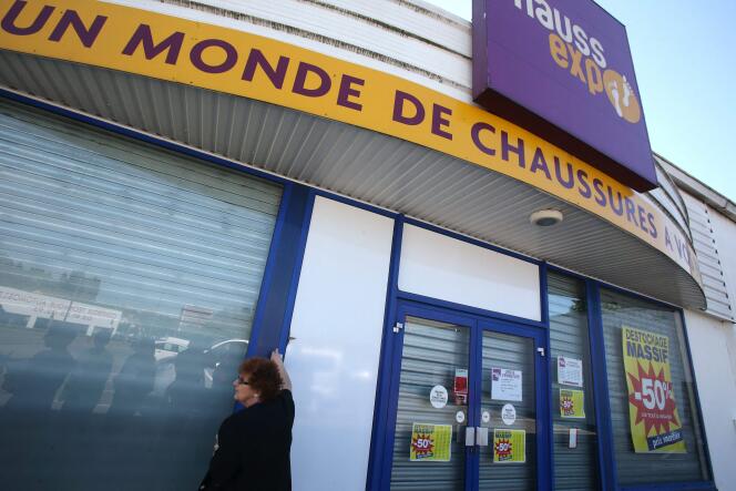 Une employée en grève baisse le rideau du magasin de chaussures Chaussexpo, à Audincourt (Doubs), en mai 2017.
