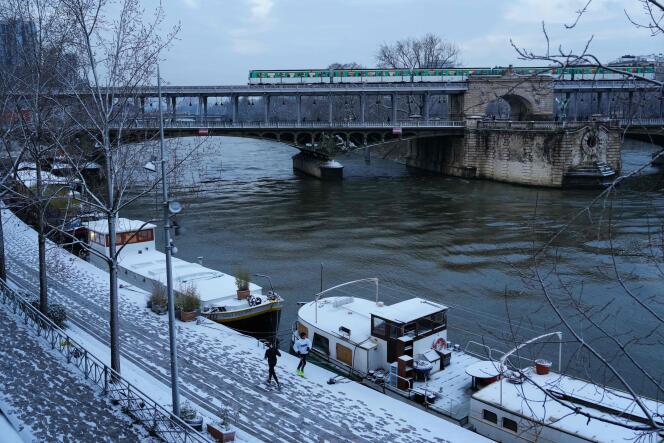 Los residentes corren por una orilla nevada del Sena en París, con el puente Bir Hakeim al fondo, el 18 de enero de 2024.