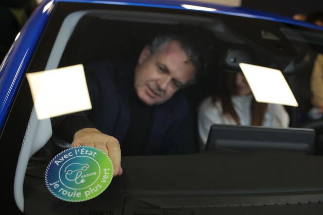 Le ministre de la transition écologique, Christophe Béchu, affiche le logo du « leasing social » sur le pare-brise de la voiture après avoir remis un véhicule au premier bénéficiaire du « leasing social », à Joinville-le-Pont (Val-de-Marne), le 22 janvier 2024.