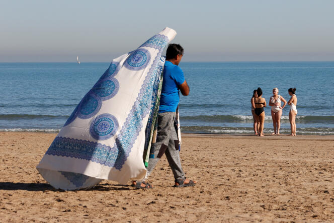 Un vendeur de serviettes marche sur une plage de Valence, en Espagne, jeudi 25 janvier.