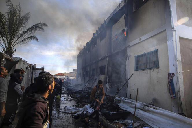 Los palestinos intentan apagar un incendio en un edificio transformado en refugio, que según la UNRWA fue atacado por tanques israelíes.  En Khan Younes, al sur de la Franja de Gaza, el 24 de enero de 2024. 