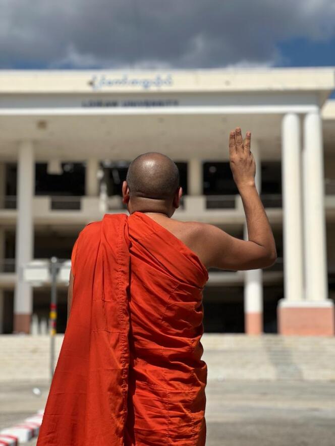 Le vénérable H. pose les doigts levés (signe de ralliement de la révolution birmane) devant l’université de Loikaw, le 27 janvier 2024.
