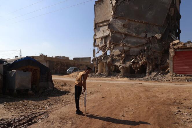 Hamza Al-Ahmed, survivant du tremblement de terre de 2023 en Syrie, devant les bâtiments détruits du camp où il vit, à Jinderes, le 4 février 2024.